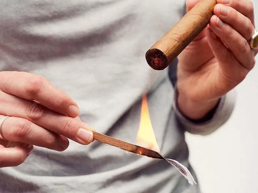 lighting up a cigar with cedar shavings